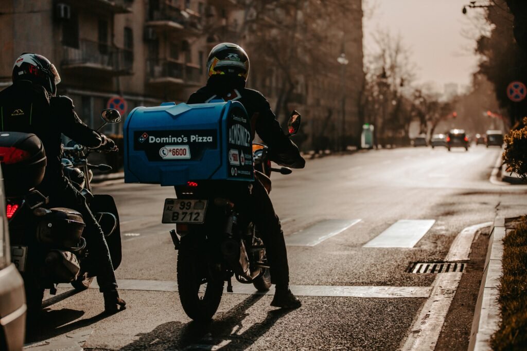 A motorcycle delivery person on a city street in Baku, Azerbaijan during the day.